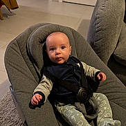 Gaspard participe au concours pour gagner de l'argent avec cette photo : baby, infant, child, bouncer, baby_seat, harness, onesie, patterned_pants, elephant_pattern, living_room, sofa, rug, tiled_floor, doorway, jacket, cozy, portrait, candid, curious_expression, indoor_lighting