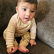 Avitaaz is registered to the contest to win money with this photo: baby, barefoot, brown_couch, casual_clothing, child, couch, cozy, curious, cute, dinosaur_pants, expression, footwear_free, home, indoors, infant, portrait, sitting, small_hands, striped_shirt, young