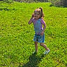 Kyleigh is registered to the contest to win money with this photo: child, girl, smiling, grass, outdoor, nature, sunlight, greenery, shorts, tshirt, shoes, pony_tail, happy, playful, summer, field, casual_clothing, young_child, daylight, portrait