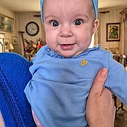 Hortense a rejoint le concours — aidez-le/la à gagner de superbes lots ! adult_hand, baby, blue_clothing, blue_headband, child, curious, cute, decor, face, flower_headband, hand, holding, home, indoor, infant, person, portrait, smile, warm_lighting, wide_eyes