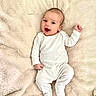 baby, infant, smiling, white_onesie, fluffy_blanket, lying_down, happy, cute, child, person, portrait, cozy, soft_texture, indoors, newborn, skin, head, hand, footed_pajamas, sleepwear