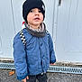 Rafaël a rejoint le concours — aidez-le/la à gagner de superbes lots ! child, toddler, blue_jacket, black_beanie, scarf, backpack, sneakers, pavement, door, outdoor, curious, standing, casual_clothing, street, urban, young_child, fall, cold_weather, person, portrait