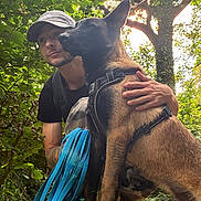 Blaz a rejoint le concours — aidez-le/la à gagner de superbes lots ! animal, camouflage, canine, crouching, dog, forest, greenery, hand, harness, hat, leaf, leash, man, nature, outdoor, path, pet, sunlight, tattoo, trees