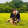 Blaz participe au concours pour gagner de l'argent avec cette photo : animal, canine, casual_clothing, companion, crouching, daylight, dog, field, grass, greenery, happy, loyalty, man, nature, outdoor, person, pet, portrait, stick, tree