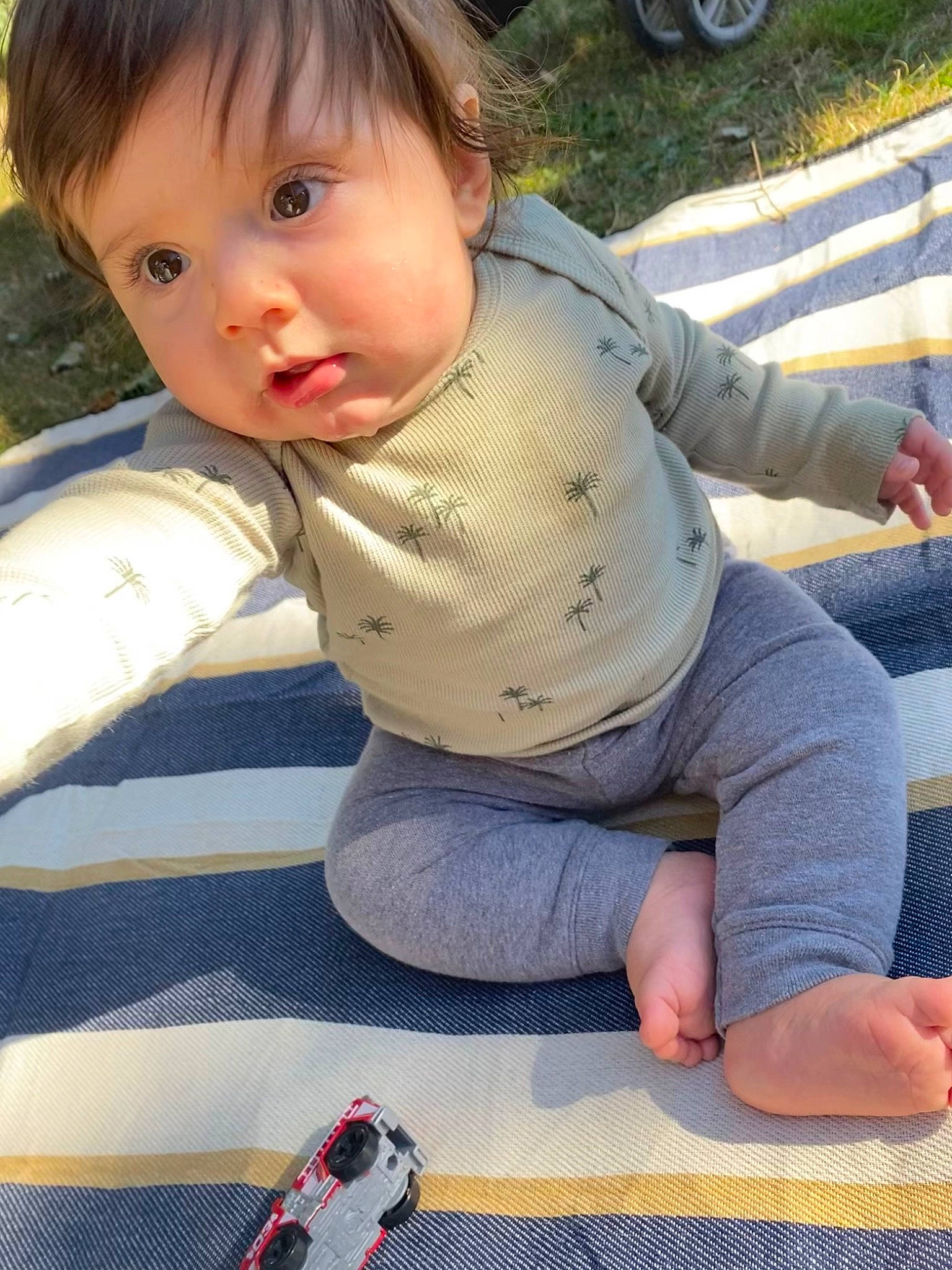 Brycen is registered to the contest to win money with this photo: baby, baby_toddler_clothing, flooring, foot, fun, grass, hand, human_leg, joint, knee, leisure, pattern, person, recreation, sitting, sleeve, thigh, tire, toddler, wheel