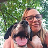woman, dog, glasses, smile, tongue_out, happy, outdoor, tree, leaves, nature, selfie, portrait, pet, canine, human, bracelet, friendship, closeup, sunlight, casual