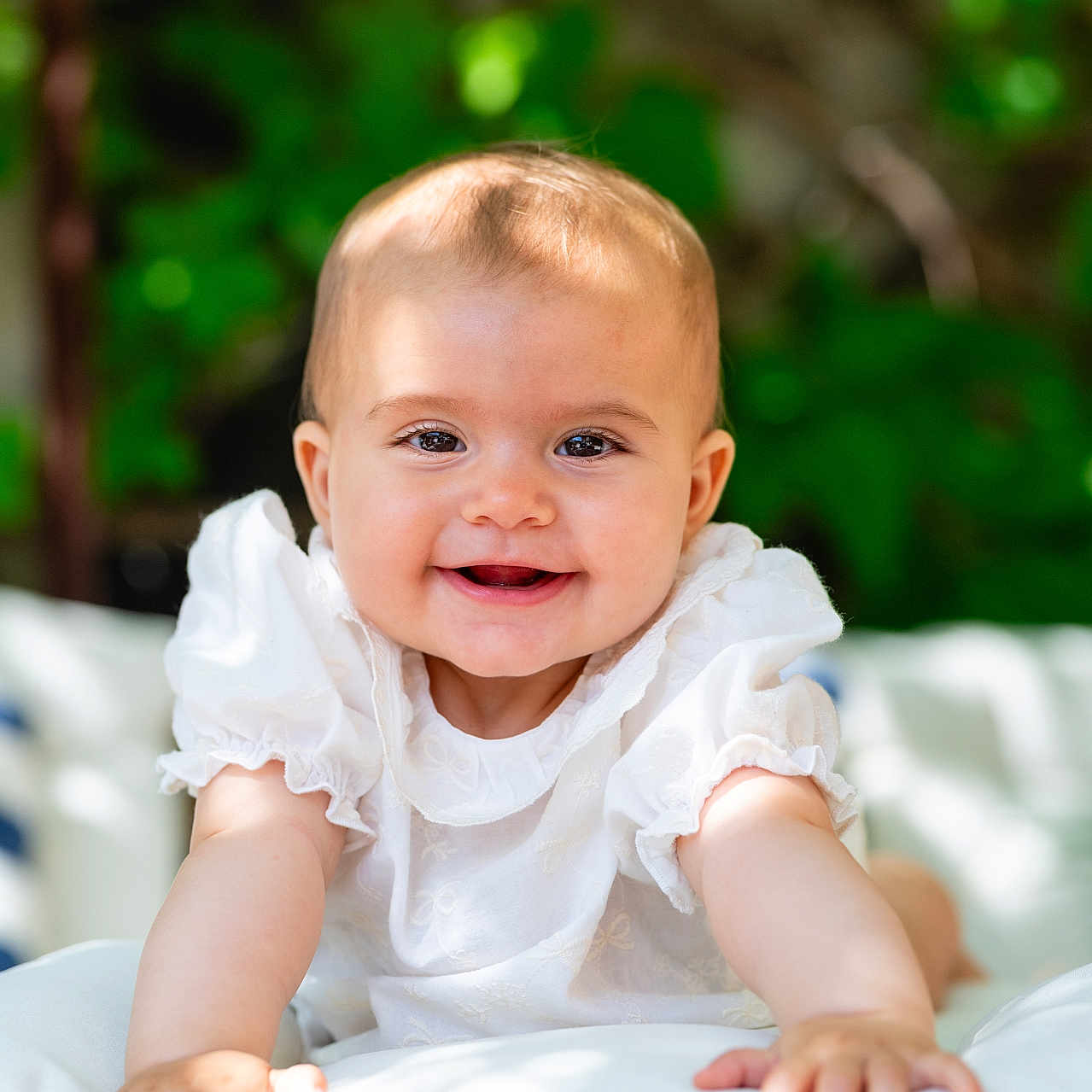 Pia a rejoint le concours — aidez-le/la à gagner de superbes lots ! baby, blurred_background, child, closeup, cushion, cute, daylight, face, greenery, hands, happy, infant, nature, outdoor, portrait, smiling, soft_texture, sunlight, toddler, white_clothing
