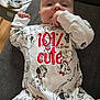 baby, infant, onesie, clothing, 101_dalmatians, cute, hand, face, lying_down, indoor, fabric, red_text, black_and_white, cartoon, animal_print, child, person, soft_toys, playful, sucking_hand