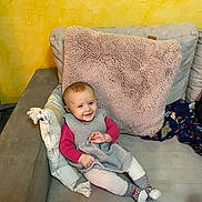 Joy a rejoint le concours — aidez-le/la à gagner de superbes lots ! baby, casual, child, couch, cozy, cute, furniture, happy, home, indoor, knitted_dress, person, pillow, relaxed, seated, smiling, soft_texture, striped_socks, toddler, yellow_wall