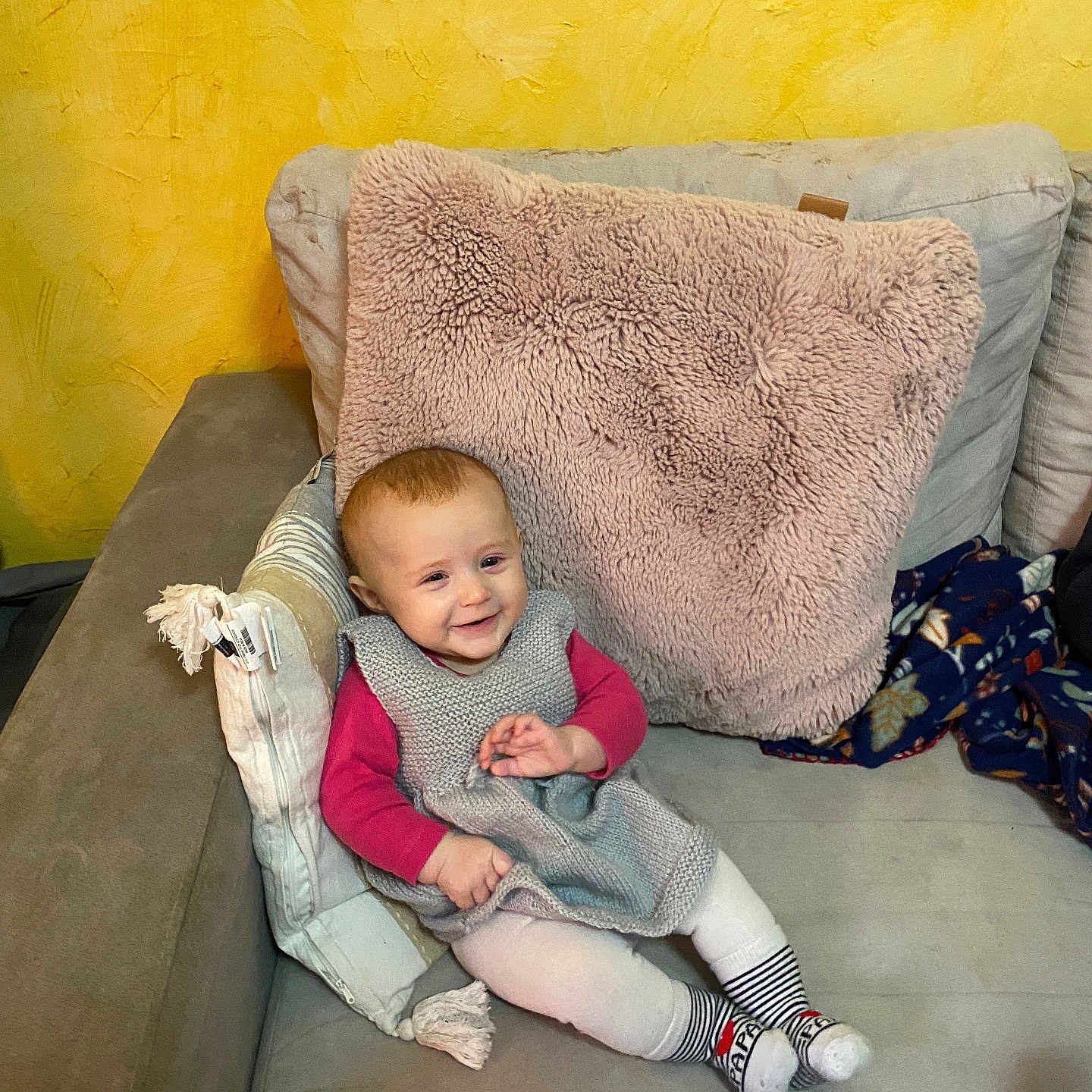 Joy a rejoint le concours — aidez-le/la à gagner de superbes lots ! baby, casual, child, couch, cozy, cute, furniture, happy, home, indoor, knitted_dress, person, pillow, relaxed, seated, smiling, soft_texture, striped_socks, toddler, yellow_wall
