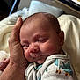 baby, infant, newborn, sleeping, cheeks, face, hand, palm, blanket, onesie, cozy, portrait, close_up, peaceful, domestic_interior, fabric, skin, eyelids, support, cuddle