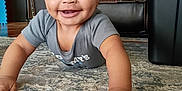Jakai is registered to the contest to win money with this photo: baby, crawling, smiling, indoor, carpet, rug, child, happy, face, person, living_room, furniture, leather_chair, storage_bin, home, cute, hands, eyes, short_sleeve, toddler