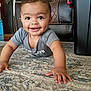baby, crawling, smiling, indoor, carpet, rug, child, happy, face, person, living_room, furniture, leather_chair, storage_bin, home, cute, hands, eyes, short_sleeve, toddler