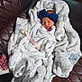 Kai is registered to the contest to win money with this photo: newborn, baby, blanket, bow, sleeping, wrapped, quilted_leather, snowflake_pattern, soft_texture, indoor, cozy, infant, headwear, resting, comfort, fabric, person, cute, peaceful, wrapped_up