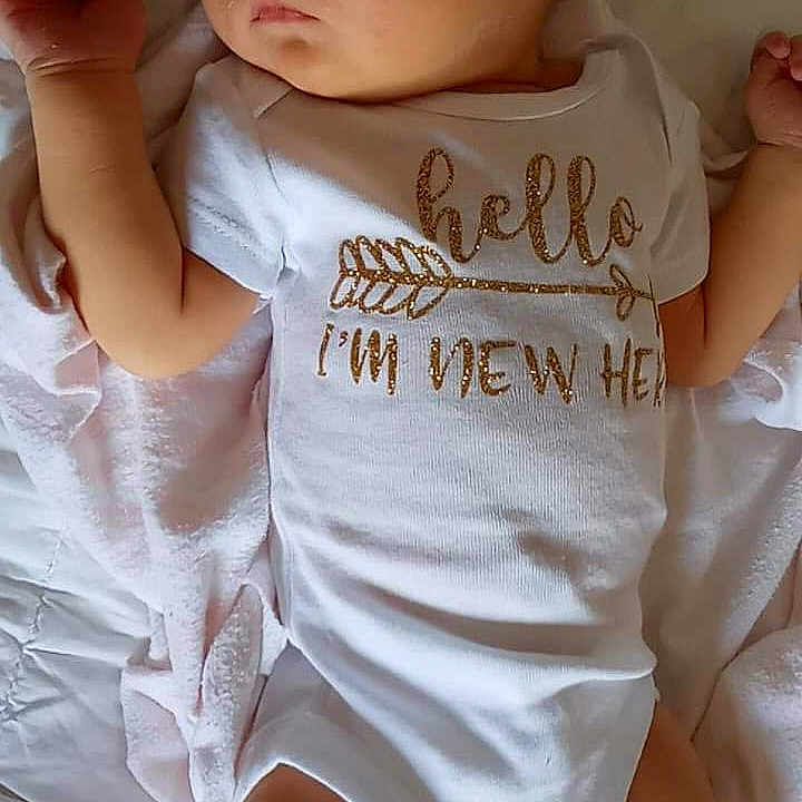 Charlotte is registered to the contest to win money with this photo: baby_toddler_clothing, chin, eye, eyelash, facial_expression, hairstyle, hand, happy, human, human_body, lip, mouth, muscle, neck, shorts, shoulder, skin, sleeve, textile, white