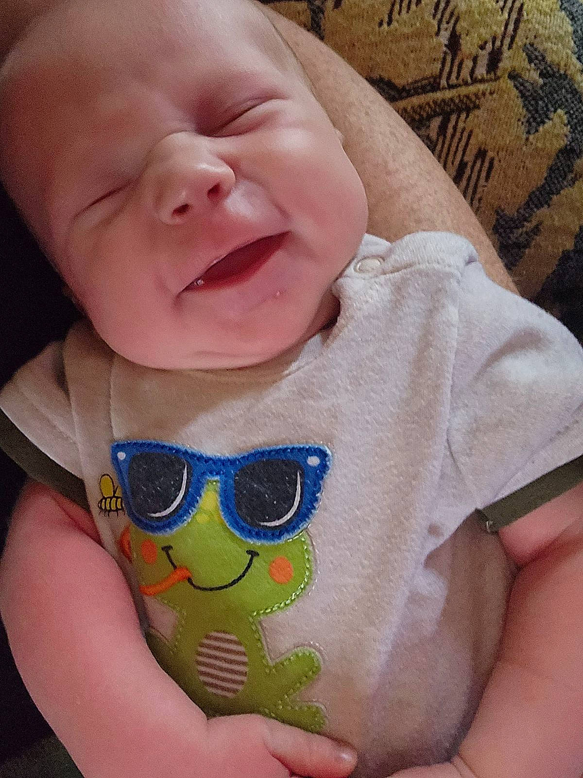 Brett is registered to the contest to win money with this photo: arm, baby, baby_toddler_clothing, cheek, chin, clothing, eye, face, happy, head, human_body, iris, lip, mouth, neck, nose, person, skin, sleeve, smile