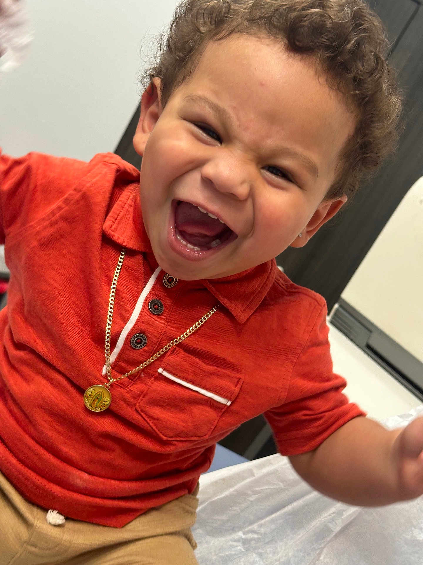 Nekoda joined the competition — help win amazing prizes! child, toddler, smiling, curly_hair, orange_shirt, gold_necklace, happy, indoor, portrait, cute, person, laughing, casual_clothing, young, face, human, joy, emotion, closeup, seated