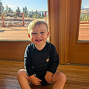 Braxton joined the competition — help win amazing prizes! child, toddler, smiling, sitting, wooden_floor, glass_door, sunlight, indoor, black_clothing, happy, blonde_hair, face, person, cute, portrait, natural_light, home, window, floor, baby