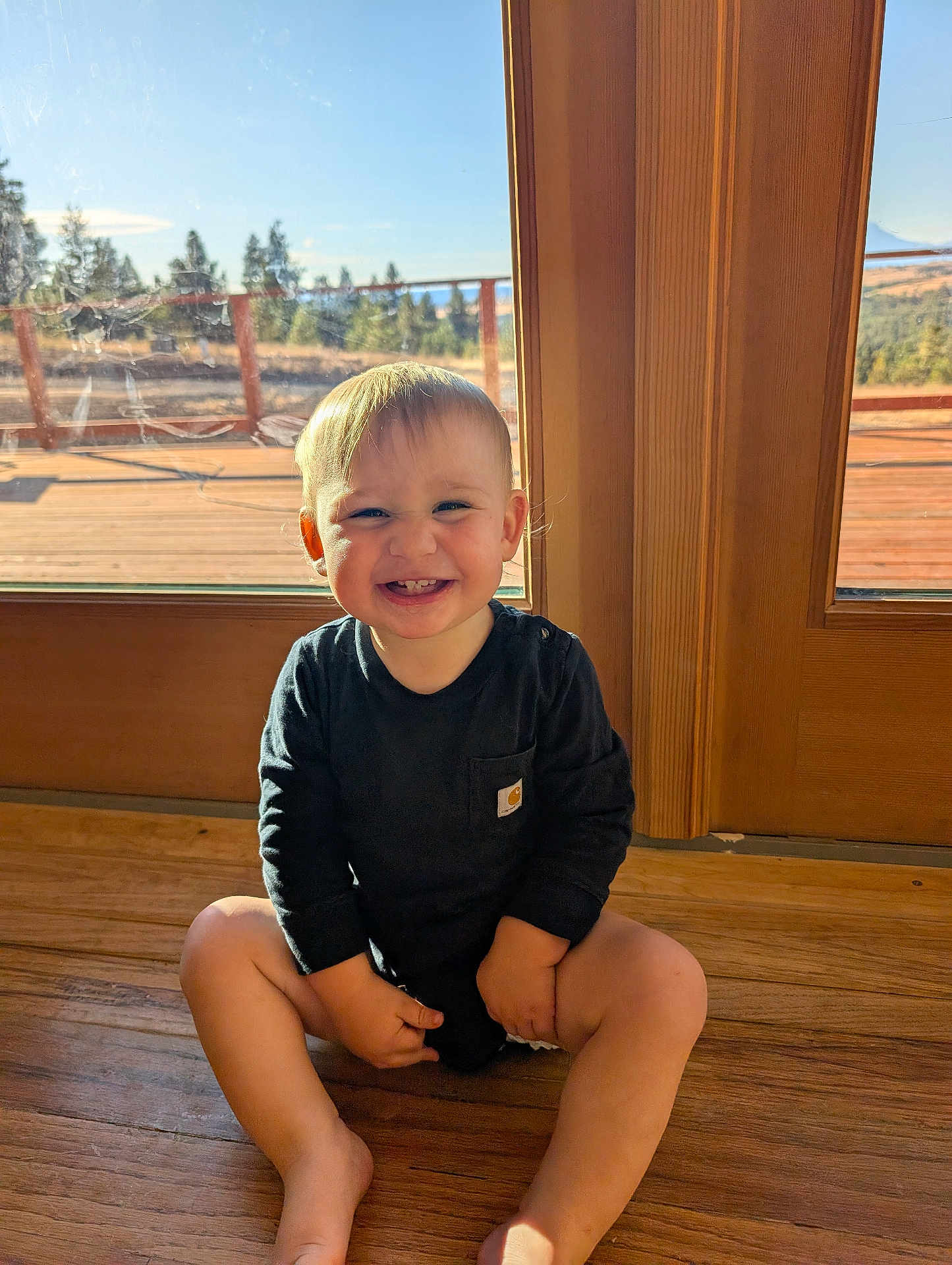 Braxton joined the competition — help win amazing prizes! child, toddler, smiling, sitting, wooden_floor, glass_door, sunlight, indoor, black_clothing, happy, blonde_hair, face, person, cute, portrait, natural_light, home, window, floor, baby