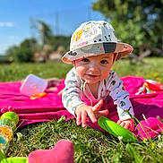 Adam participe au concours pour gagner de l'argent avec cette photo : baby, child, hat, grass, blanket, toy, outdoor, sunny, smiling, crawling, greenery, playtime, nature, infant, colorful, daylight, happy, casual_clothing, closeup, summer