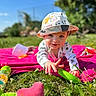 baby, child, hat, grass, blanket, toy, outdoor, sunny, smiling, crawling, greenery, playtime, nature, infant, colorful, daylight, happy, casual_clothing, closeup, summer