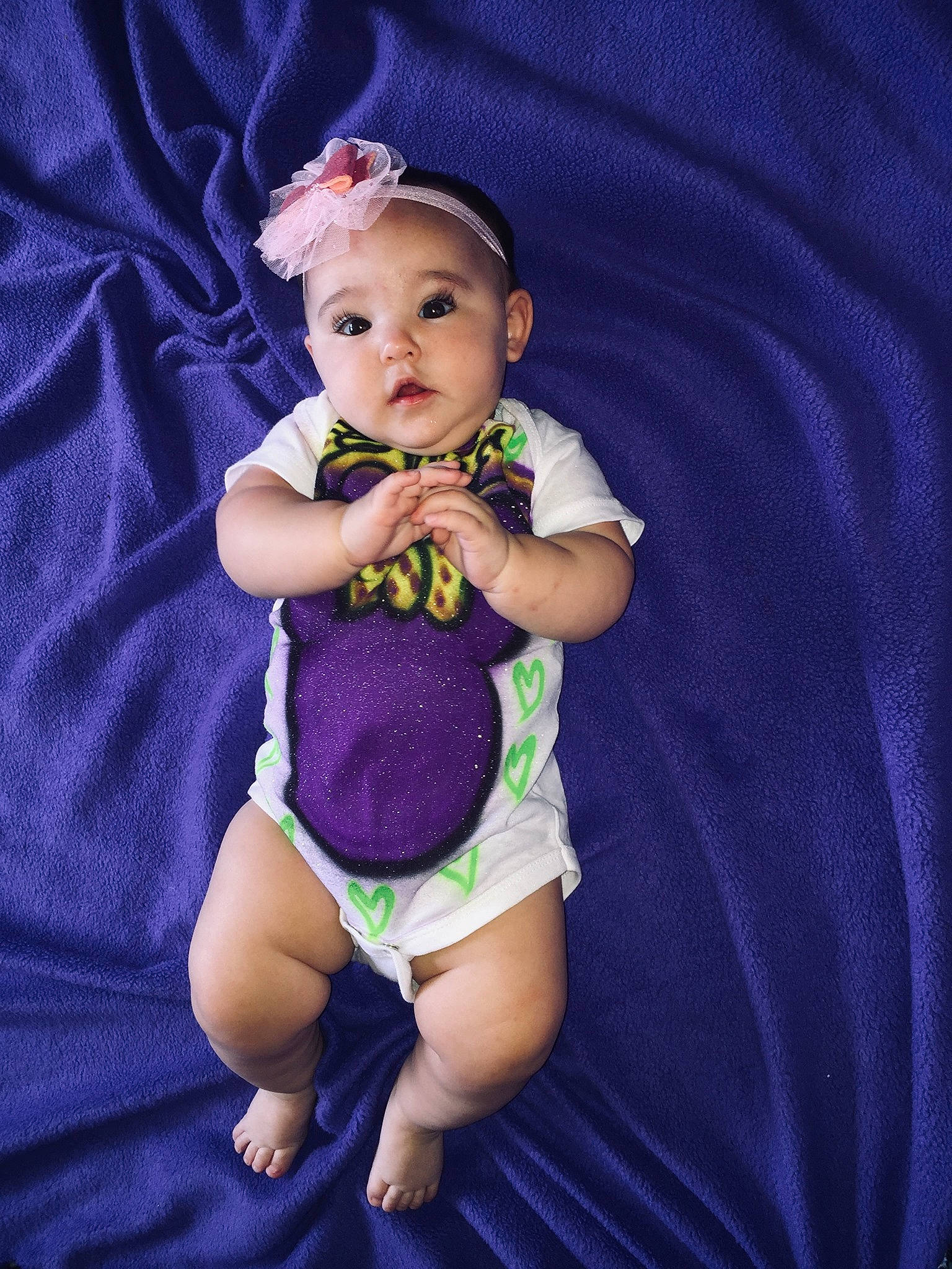 Ellie is registered to the contest to win money with this photo: arm, baby, baby_toddler_clothing, cheek, child, finger, iris, person, photography, product, purple, sitting, skin, smile, toddler