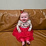 Olivia is registered to the contest to win money with this photo: baby, child, smile, dress, red_skirt, long_sleeve_shirt, reindeer_pattern, candy_cane, hair_bow, barefoot, couch, leather, indoor, happy, sitting, infant, cute, holiday_theme, person, portrait