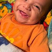 Brahim joined the competition — help win amazing prizes! baby, smiling, orange_shirt, blanket, colorful, portrait, happy, infant, face, child, cute, lying_down, toddler, clothing, warm, cozy, indoors, skin, expression, young