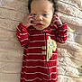 Kazire is registered to the contest to win money with this photo: baby, infant, onesie, red_clothing, striped, bear_patch, blanket, fluffy, soft_texture, lying_down, hands_near_face, curious_expression, indoors, portrait, child, cute, young, sleepwear, comfortable, warm