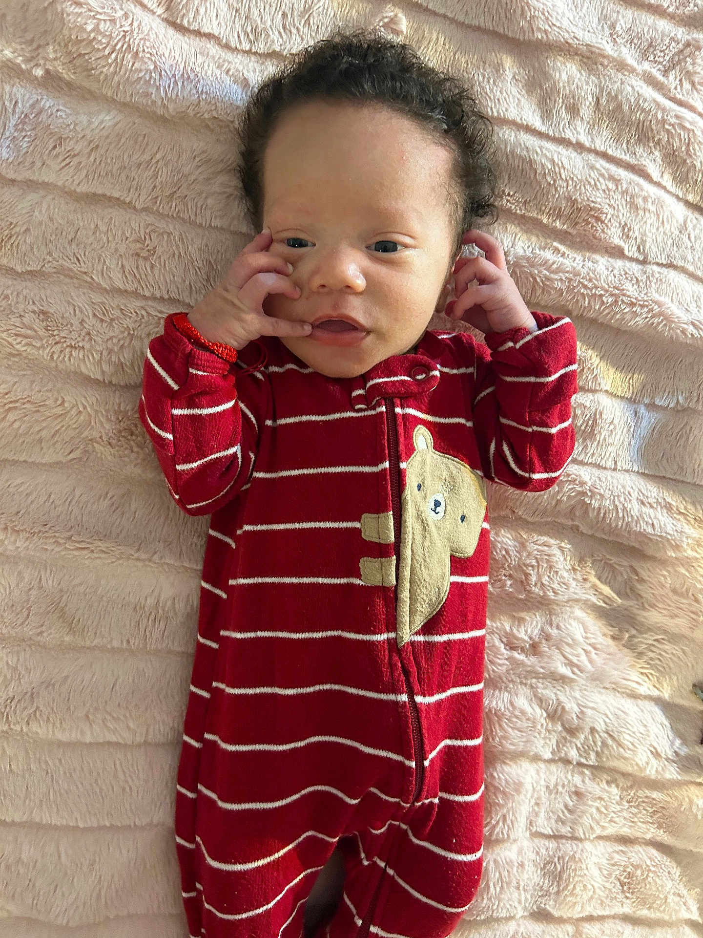 Kazire is registered to the contest to win money with this photo: baby, infant, onesie, red_clothing, striped, bear_patch, blanket, fluffy, soft_texture, lying_down, hands_near_face, curious_expression, indoors, portrait, child, cute, young, sleepwear, comfortable, warm