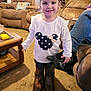 Sophia is registered to the contest to win money with this photo: boots, carpet, casual, child, coffee_table, couch, cute, furniture, girl, hair_tie, home, indoor, living_room, long_sleeve_shirt, person, playful, polka_dots, smile, sock, toy