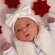 Emma participe au concours pour gagner de l'argent avec cette photo : baby, infant, white_bow, fluffy_vest, red_roses, pink_background, cute, newborn, portrait, face, headwear, soft_texture, small_fists, lying_down, closeup, adorable, baby_clothing, decorative_flowers, innocent, expression