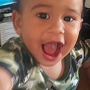 Axel is registered to the contest to win money with this photo: toddler, child, face, smile, open_mouth, camouflage, shirt, indoor, person, happy, eyes, hand, closeup, baby, expression, young_child, blur, background, technology, computer_screen