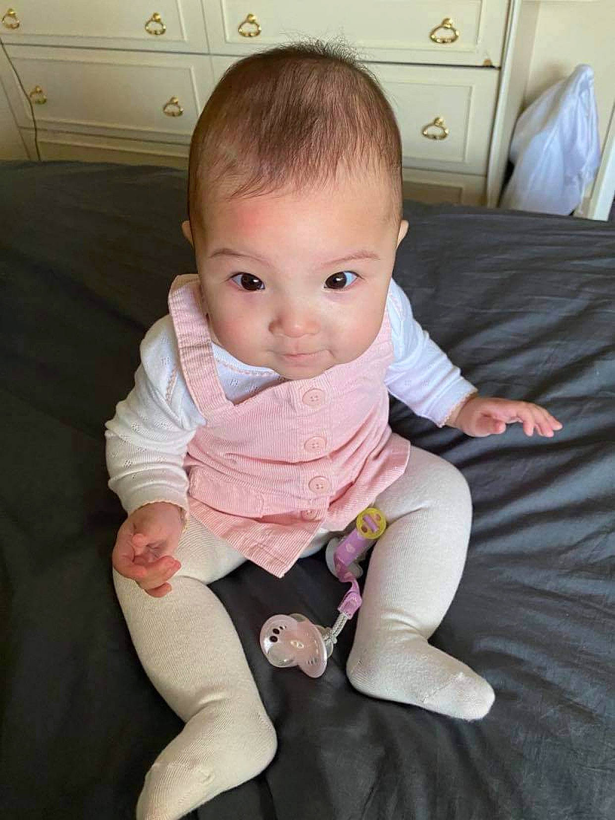 Ella-mai is registered to the contest to win money with this photo: baby_toddler_clothing, bed, bedding, bedroom, cabinetry, cheek, chest_of_drawers, child, comfort, drawer, dresser, grey, home, human, linens, person, pink, room, sitting, skin