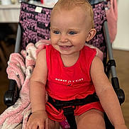 Maëlhya a rejoint le concours — aidez-le/la à gagner de superbes lots ! toddler, child, smile, red_dress, stroller, blanket, indoor, happy, blue_eyes, baby, seatbelt, person, cute, skin, hand, face, hair, clothing, pink, black