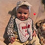 baby, infant, headband, bib, smile, sitting, converse_shoes, yellow_pants, blanket, cute, indoors, child, happy, soft_texture, red_heart_emoji, clothing, footwear, portrait, cozy, young_child