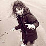 Mila participe au concours pour gagner de l'argent avec cette photo : beach, casual_clothing, child, coat, curly_hair, feet, fun, happy, jacket, nature, outdoor, person, playful, pointing, portrait, sand, smiling, white_sneakers, wind, young