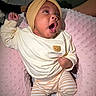 Saige is registered to the contest to win money with this photo: baby, infant, headband, bow, yellow, sweater, bear_patch, yawning, pink_pillow, striped_pants, cozy, cute, child, person, indoor, soft_texture, clothing, sitting, adorable, portrait