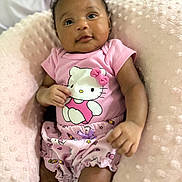 Saige is registered to the contest to win money with this photo: baby, infant, pink_clothing, hello_kitty, cushion, soft_texture, smiling, portrait, child, cute, comfortable, indoors, closeup, baby_girl, apparel, seated, happy, skin, face, hand