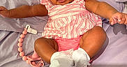 Saige joined the competition — help win amazing prizes! arms, baby, bed_sheet, bow, child, cute, happy, headband, indoors, infant, lavender, legs, lying_down, pacifier_clip, person, pink_clothing, portrait, skin, smiling, white_socks