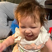 Myonie joined the competition — help win amazing prizes! baby, child, messy_hair, dress, indoor, pillow, bed, furniture, person, clothing, face, expression, scrunched_face, sitting, bookshelf, room, curtain, colorful, young_child, infant