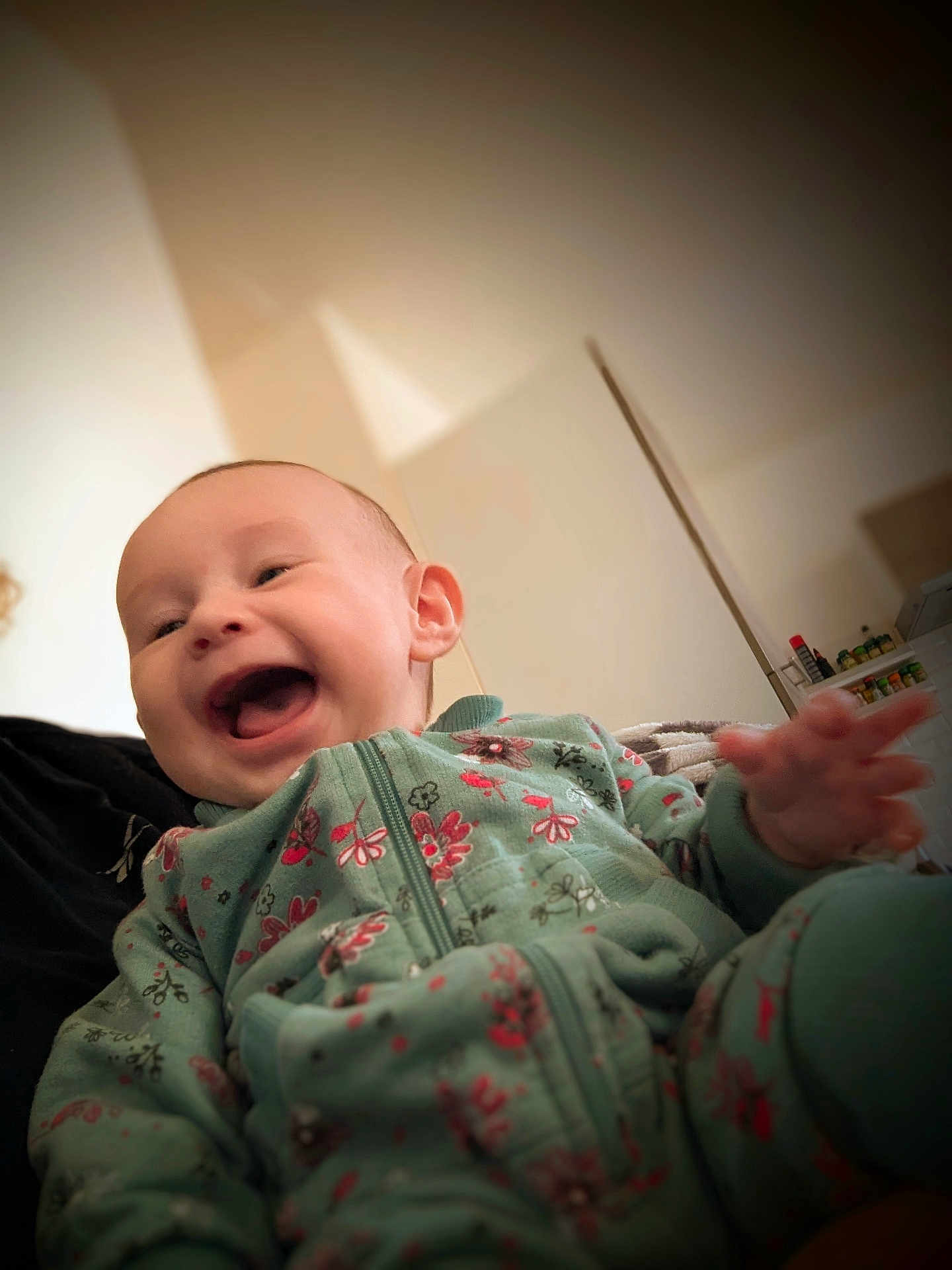 Héloïse a rejoint le concours — aidez-le/la à gagner de superbes lots ! baby, child, smiling, laughing, onesie, floral_pattern, green_clothing, indoor, person, face, hand, infant, happiness, joy, cute, portrait, soft_light, warm_tones, blurred_background, cozy