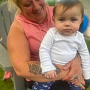 Bonnie joined the competition — help win amazing prizes! woman, baby, child, smiling, holding, outdoor, grass, chair, tattoo, ring, hoodie, long_sleeve, pants, rainbow_pattern, face, person, happy, closeup, nature, family