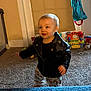 Jaxton joined the competition — help win amazing prizes! child, toddler, baby, leather_jacket, smile, motion_blur, indoor, carpet, toys, playroom, standing, happy, face, window_shade, doorway, colorful_toy, hanging_bag, plush_toy, pajama_pants, flooring