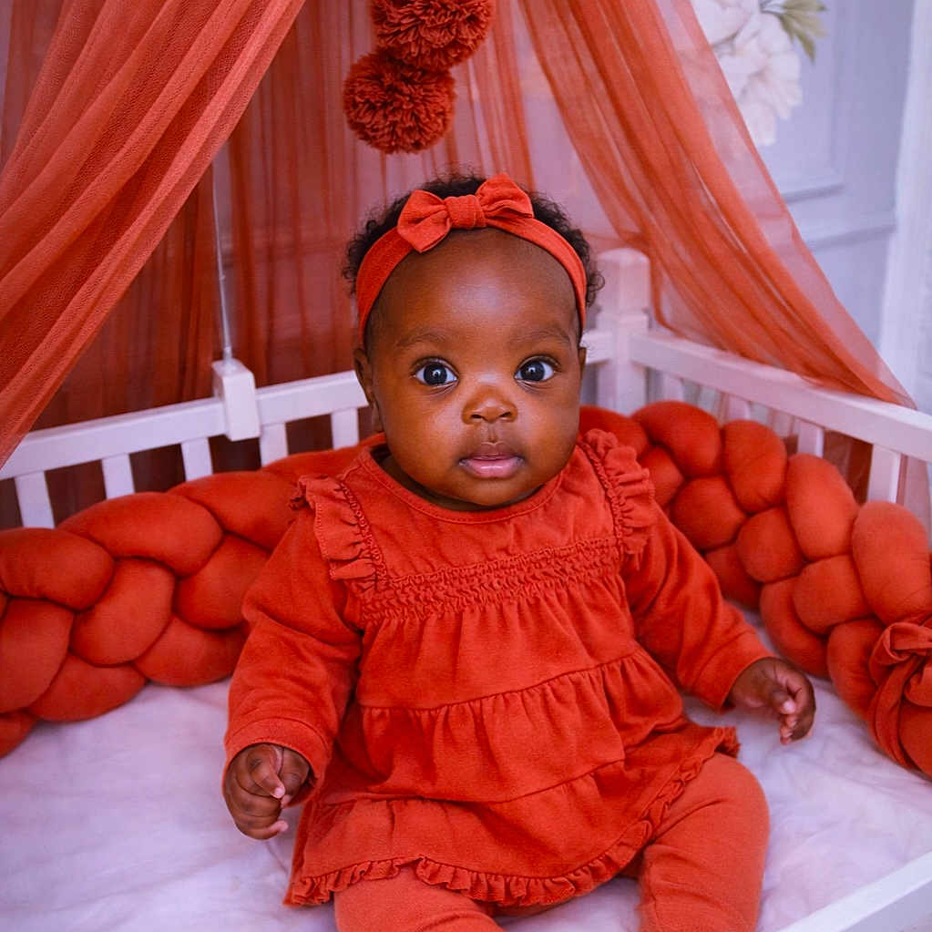 Sophie-Veille Léna participe au concours pour gagner de l'argent avec cette photo : baby, braided_cushion, child, crib, curtains, cute, decor, fabric, head, headband, homedecor, indoor, infant, orange_clothing, person, portrait, sitting, soft_furniture, toddler, wide_eyes