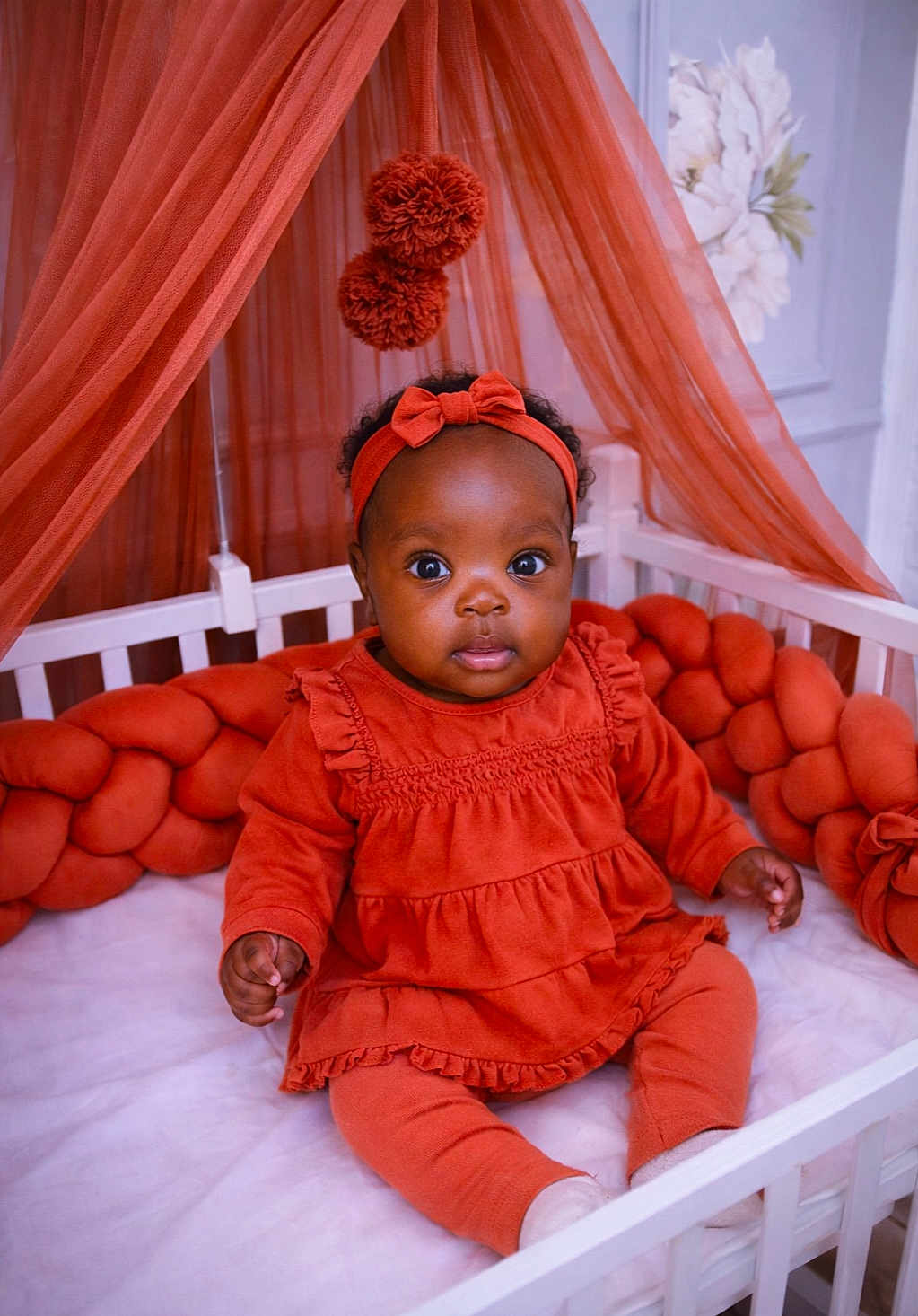 Sophie-Veille Léna participe au concours pour gagner de l'argent avec cette photo : baby, child, crib, orange_clothing, headband, braided_cushion, curtains, indoor, portrait, infant, cute, wide_eyes, sitting, soft_furniture, decor, fabric, person, head, homedecor, toddler