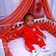 Sophie-Veille Léna a rejoint le concours — aidez-le/la à gagner de superbes lots ! baby, child, crib, red_clothing, tracksuit, adidas, sneakers, orange_canopy, orange_cushions, indoor, portrait, cute, infant, sitting, white_furniture, plush, curly_hair, looking_at_camera, cozy, home