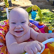 Phoenix is registered to the contest to win money with this photo: baby, babywalker, cheerful, child, closeup, colorful, cute, face, grass, hand, happy, infant, nature, outdoor, person, plastic, play, smile, sunlight, toy