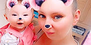 Azzalia is registered to the contest to win money with this photo: woman, baby, selfie, pink_bear_ears, pink_bear_nose, filter, sparkles, kitchen, cabinet, smile, holding, tank_top, hair_bun, cute, happy, portrait, indoor, person, child, face