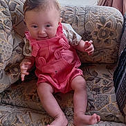 Azzalia joined the competition — help win amazing prizes! baby, child, infant, pink_romper, couch, patterned_cushion, smile, indoors, curtains, window, furniture, legs, barefoot, happy, sitting, cute, face, portrait, soft_light, cozy